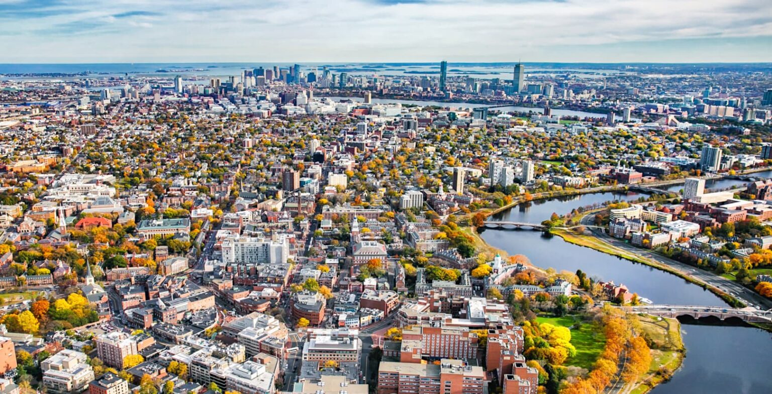 Drone shot of the City of Cambridge, MA including Harvard Square and the Charles River as the trees take on their fall colors on a clear, bright day.