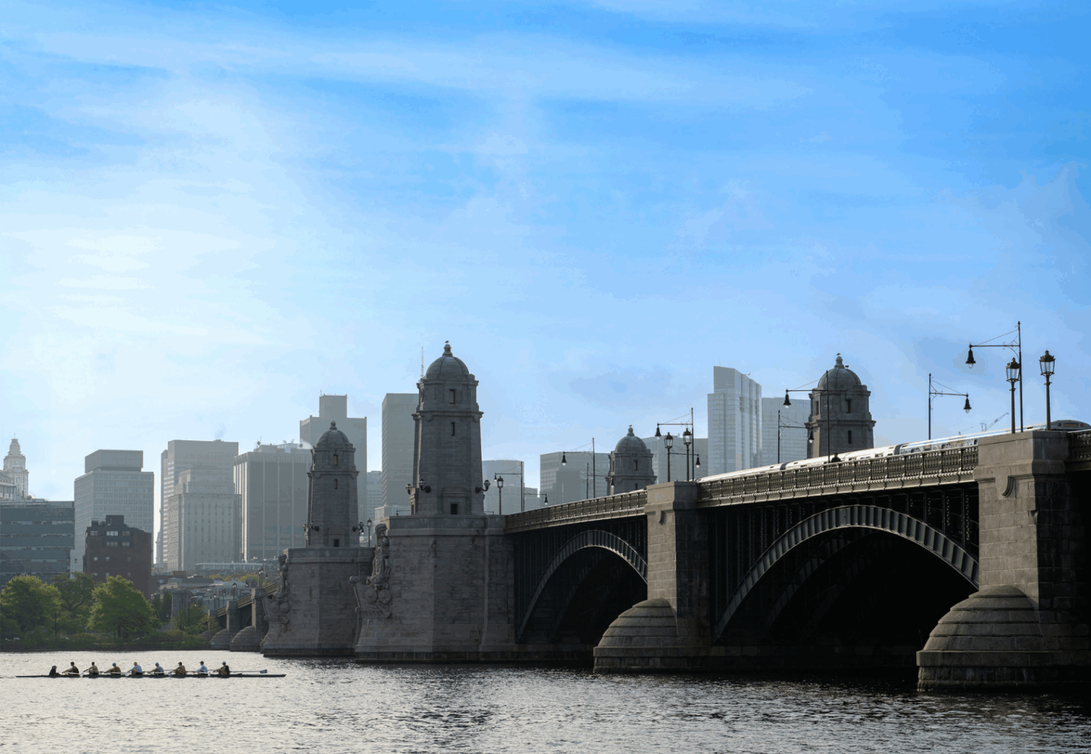 The cityscape of Cambridge MA from the water featuring the Longfellow Bridge as it spans the Charles River to connect Boston's Beacon Hill neighborhood with Kendall Square in Cambridge