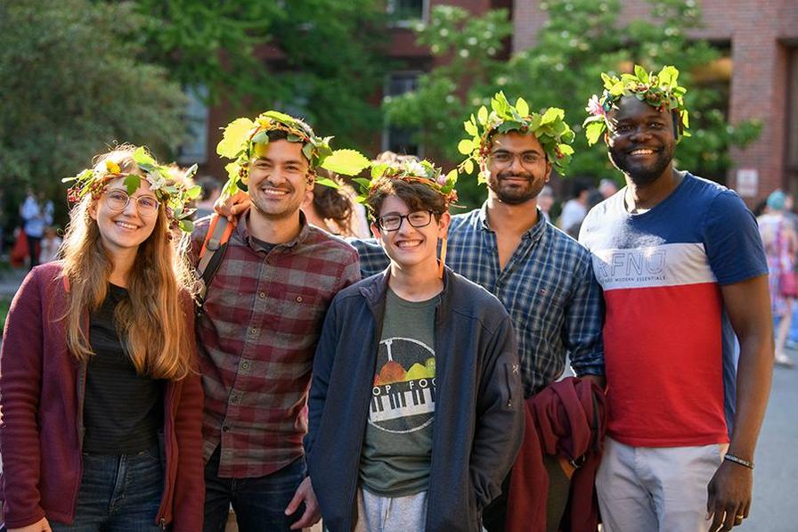 A group of five Harvard students pose outdoors in floral crowns, celebrating the Summer Solstice event at the Harvard Museum of Science and Culture.